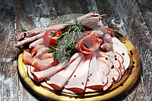 Food tray with delicious salami, pieces of sliced ham, sausage and salad. Meat platter selection