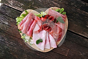 Food tray with delicious salami, pieces of sliced ham, sausage, tomatoes, salad and vegetable - Meat platter with selection.