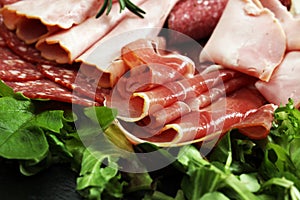 Food tray with delicious salami, pieces of sliced ham, sausage, tomatoes, salad and vegetable - Meat platter with selection