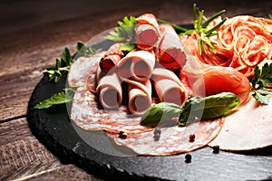 Food tray with delicious salami, pieces of sliced ham, sausages,salad and vegetable. Meat platter with selection