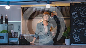 Food Truck Female Employee Hold Tasty Burger, Smiles and Looks at the Camera. Street Food Truck Se photo