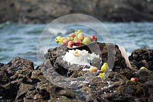 Food vase with fruits on top of a beach rock. Religious tribute