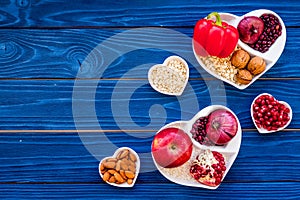 Food which help heart stay healthy. Vegetables, fruits, nuts in heart shaped bowl on blue wooden background top view