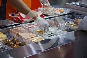 Food worker put food in plastic tray for packing