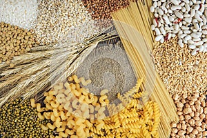 Foods high in carbohydrate on wooden background. Loaf, pasta, pearl barley and oats