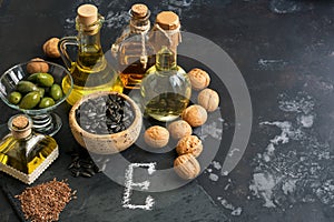 Foods rich in vitamin E on a dark rustic background. Oil, nuts, seeds. Healthy food for rejuvenation. Selective focus, copy space.