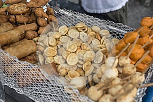 A foodstall in Manila offering freid Lumpia, Kikiam, Fishballs, Kwek Kwek and Squidballs placed in a grate