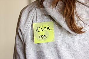 Fool'day joke. Sticker 'Kick me' on teenager girl's back