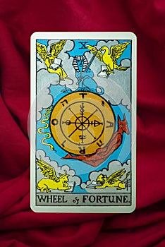 THE FOOL major tarot card of Rider Waite deck on red fabric background