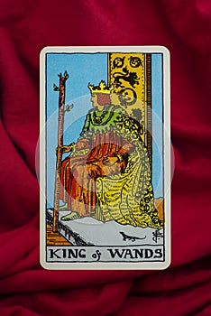 THE FOOL major tarot card of Rider Waite deck on red fabric background.