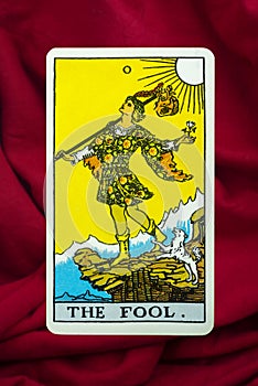 The Fool Tarot Card of Rider Waite deck on red fabric background