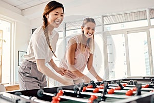 Foosball, women and friends playing table soccer in an office for fun, bonding and competition at work with happiness