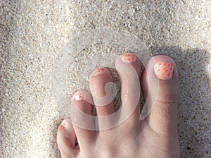 Foot on a beach with painted toe nails