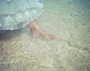 Foot of the bride touches water in the sea,with a retro effect