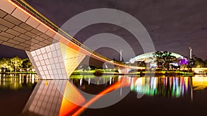 A Foot Bridge crossing a river and Sports Stadium at Night