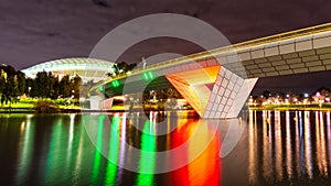A Foot Bridge crossing a river and Sports Stadium at Night