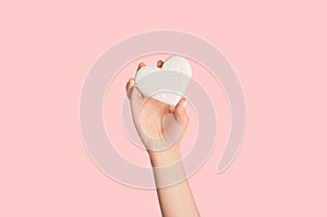 Foot care. Young girl holding heart shaped fumice on pink background, close up. Panorama