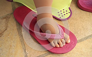 Foot of a child in a pink flip flop sandal of an adult