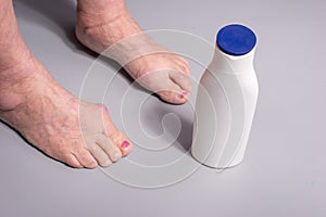 foot cream old woman applying cream from a tube to feet on a gray background