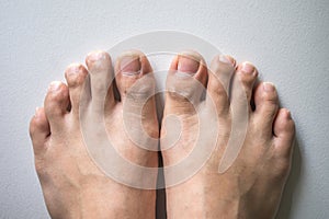 The foot and long nail toes on white concrete background.