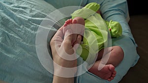 Foot massage for newborn baby at home. Mother's hand massaging baby's feet.