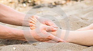 Foot massage in sand, male and female caucasian