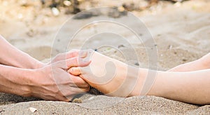 Foot massage in sand, male and female caucasian