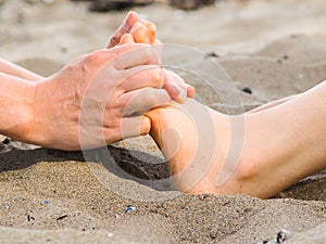 Foot massage in sand, male and female caucasian