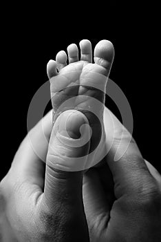 The foot of a newborn baby in the hands of his father. Baby foot and male fingers photo