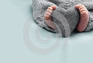 Foot of the newborn baby with wool heart, tenderness. copy space in winter concept