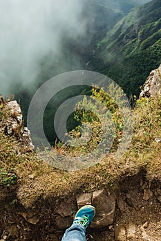 Foot over rock on the edge of deep rocky cliffs