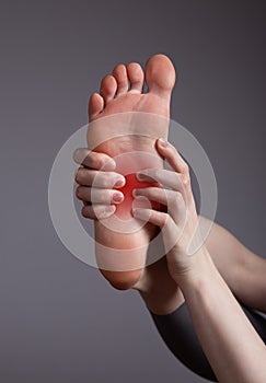 Foot pain in arch. Woman holding leg with red point closeup. Plantar fasciitis, inflammation, injuries, overuse. Health