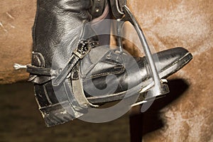 The foot of the rider in the boot with spurs in a stirrup, the side