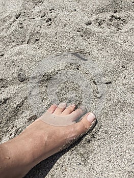 Foot on a sandy beach in summer