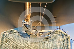 Foot of sewing machine on jeans fabric