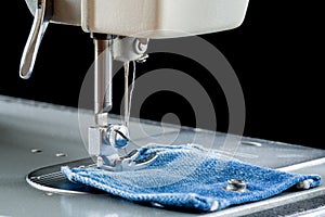 Foot of sewing machine on jeans fabric