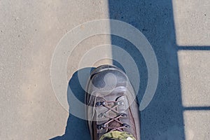 A foot shod in a military boot standing on a concrete surface.