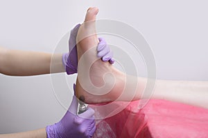 Foot skin treatment process. Gloved hands with a pedicure machine. Close-up