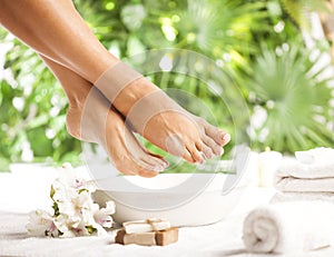 Foot spa on a tropical green leaves background