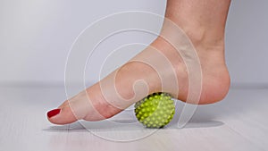 foot step on massage ball to relieve Plantar fasciitis or heel pain. woman with red pedicure massaging trigger points on