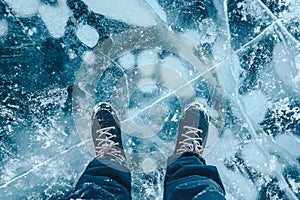 A foot of tourist standing on the cracks surface of frozen lake Baikal in the winter season of Siberia, Russia.