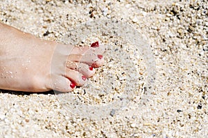 Foot of a woman in the sand on the beach