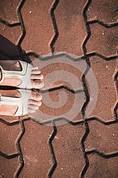 Foot woman shoe on the texture paving stone footpath background