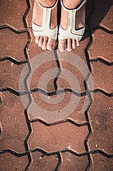 Foot woman shoe on the texture paving stone footpath background