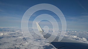 Footage airplane flight. Wing of an airplane flying above the white clouds and blue sky. beautiful aerial view from