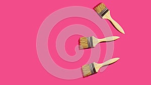 Footage of animated wooden paint varnish brushes appearing on fuchsia pink background wiggling jiggling