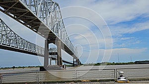 footage of the Crescent City Connection bridge over the Mississippi River, lush green trees, blue sky and clouds in New Orlean
