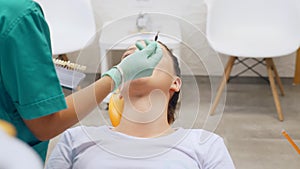 Footage of a dentist checking a young woman`s shade of tooth color