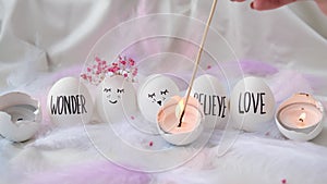 Footage of igniting a candle in Easter eggs Composition. Easter eggs with painted smiley faces. Cozy home interior decor