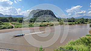 footage of Long tail boat in river with big mountain background in Thailand